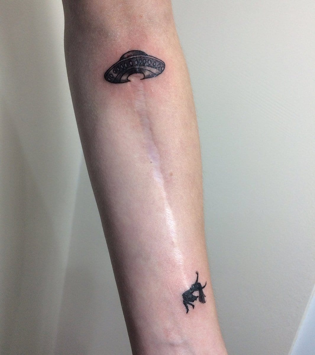 This long scar on this person’s arm has been turned into a beam from an alien spacecraft beaming up a woman. As with most tattoos, this one must have some significance in this person’s life. I wonder if they are a believer in aliens or have been abducted themselves at some point.